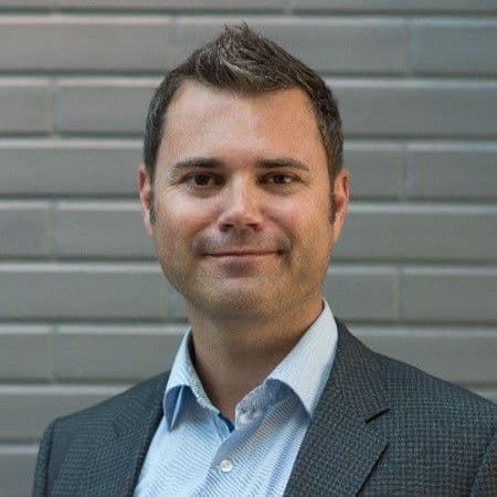 Thorstein som smiler i lys skjorte og mørk blazer med kort hår. Foto.