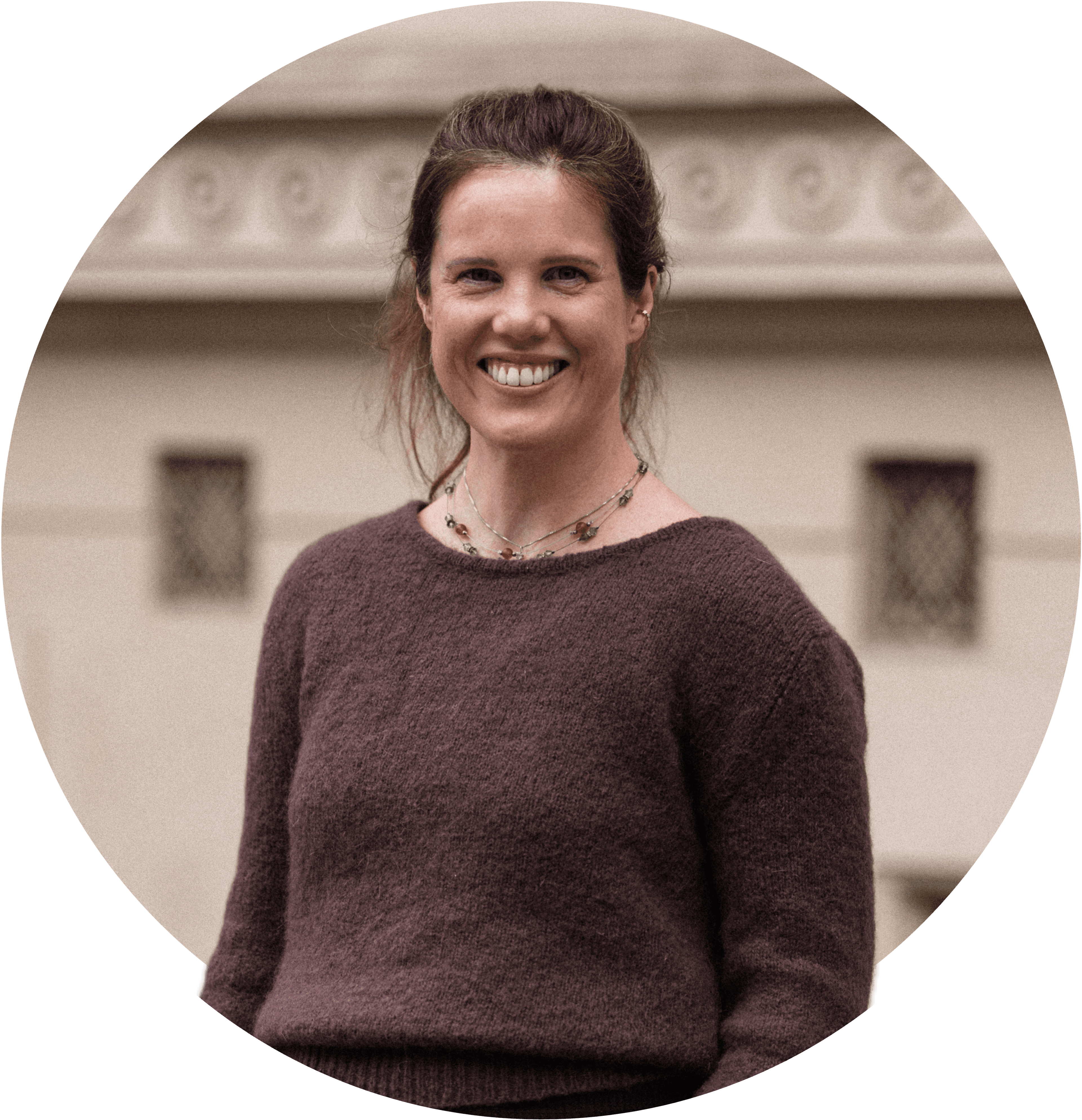 Linn smiler, iført brun genser og med håret i hestehale. Foto.