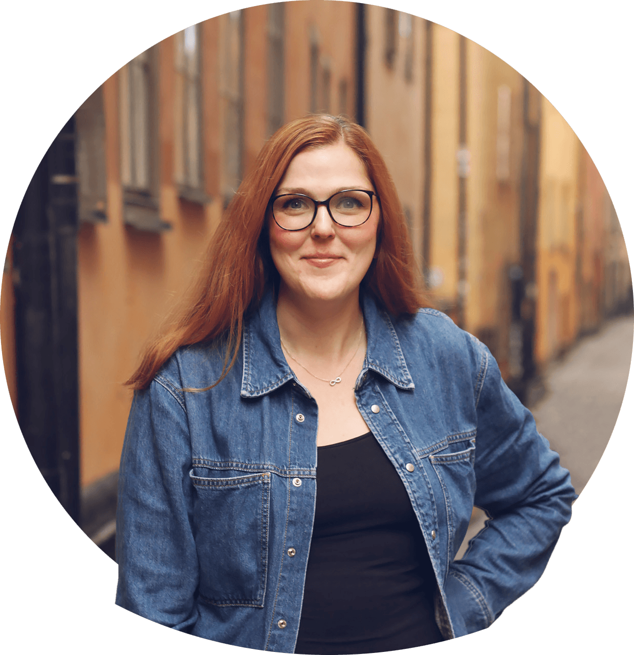 Line med briller på og halvblondt hår i hestehale, smilende kledd i mørk bluse. Foto.